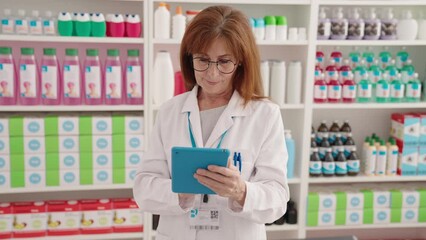 Canvas Print - Middle age woman pharmacist using touchpad working at pharmacy