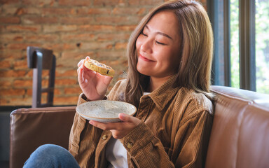 Wall Mural - Portrait image of a beautiful young asian woman holding and eating a piece of cookie