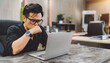 © tai - Asian business man stressed sitting headache. exhausted male employee have migraine while busy working at office. a looking tired guy work late overwork touch face because pain from office syndrome