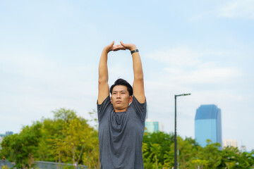 Urban sports - Asian young man is doing warming up before running in the city on a beautiful summer day