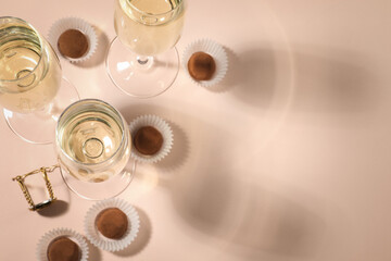 Sticker - Glasses of delicious sparkling wine and chocolate truffles on pale pink background, above view. Space for text