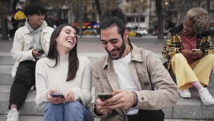 Wall Mural - Smiling couple using smartphone and laughing outdoors. People and technology having fun. High quality photo