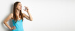 Young woman drinking water from a glass on a white background. Banner