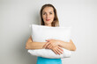 © Alex - Smiling young woman in tank top holding pillow on white background