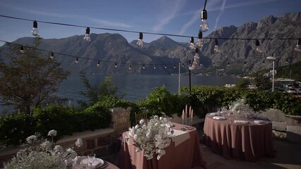Wall Mural - Festive tables with bouquets stand on the terrace against the backdrop of mountains