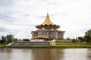 Kuching Malaysia Sep 3rd 2022: the view of Sarawak river and New Sarawak State Legislative Assembly Building. 
The cross-section of the building is designed like a nine-pointed star.