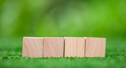 Wall Mural - Stacking blank wooden cubes on green background with copy space for input wording and infographic icon. Empty brown wooden object block for symbol icon put technology, zero gravity, business concept.