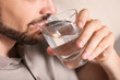 Man drinking water on blurred background, closeup. Refreshing drink