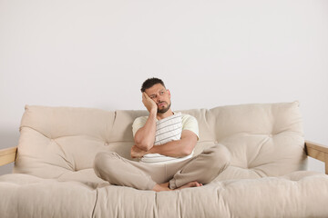 Wall Mural - Sleepless man hugging pillow on sofa at home