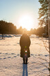 Back view of woman standing in snow and looking at sun light. Peaceful winter atmosphere. Spending time alone.