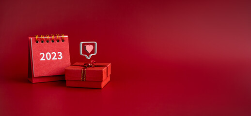 3d love like heart icons floating on small red present gift box with 2023 year of desk calendar on red background with copy space. Special gift banner for Valentine's Day,  birthday and anniversaries.