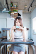 © 周平 大竹 - 自宅でイスに座りカップを持ちながらカメラ目線で笑顔を見せる日本の若い女性