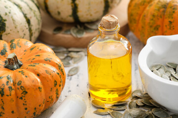 Wall Mural - Pumpkin seeds oil bottle, pumpkins and mortar of seeds on wooden kitchen table.