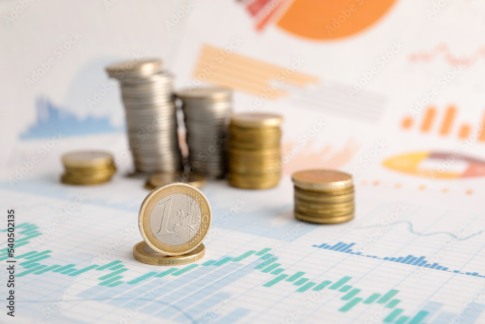 Stacks of coins on diagrams, closeup. Exchange rate concept