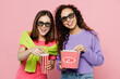 © ViDi Studio - Young two friends laughing happy women in 3d glasses watch movie film hold bucket of popcorn cup of soda pop in cinema look camera isolated on pastel plain light pink color background studio portrait.
