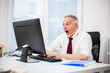 © Minerva Studio - Senior manager in a surprised expression in front of his pc monitor