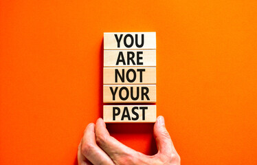 Wall Mural - You are not your past symbol. Concept words You are not your past on wooden blocks. Businessman hand. Beautiful orange table orange background. Business and you are not your past concept. Copy space.