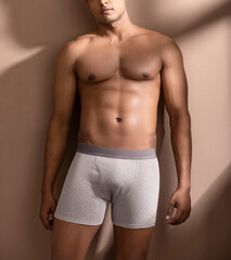 Cropped shot of muscular young man wearing underwear isolated on white background. 