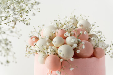 Canvas Print - Wedding cake with pink cream cheese frosting decorated with chocolate spheres and field  gypsophila flowers on the white background