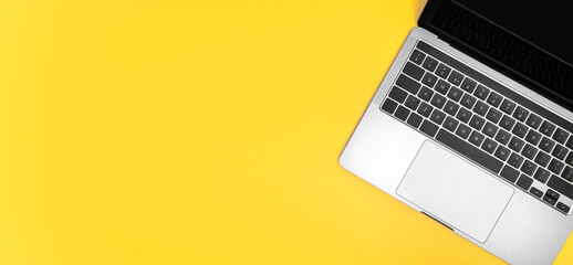 Top view of laptop on yellow background.