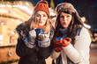 © Kzenon - Two women with hot mulled wine in cups in front of Christmas market stand