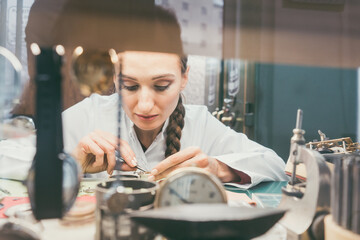 Wall Mural - Diligent woman watchmaker working diligently on repairing a watch