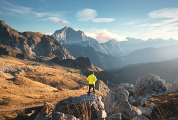 Wall Mural - man on the mountain peak and beautiful high rocks at colorful sunset in autumn in dolomites, italy. 