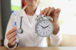 Female doctor stomatologist holding toothbrush and alarm clock in hands