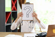 Female doctor covering face with paper with question mark