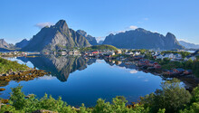 Panoramic View On Fishing Village Reine, One Of The Most Beautiful Villages In Norway. Steep Mountains At The Background. The Most Beautiful Hiking Area In Lofoten. Summer Vacation, Tourist Attraction