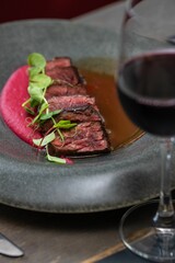 Poster - Vertical closeup of delicious Grilled wagyu beef with glass of wine on a wooden table