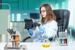 © Grispb - Student Institute of Chemistry. Woman chemist student in university laboratory. Laboratory assistant with electronic tablet. Chemist woman is sitting at desk. Concept of learning to be chemist