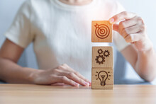 Woman Hand Holding Dartboard Above Gear And Lightbulb Icon Block. Business Planning Process, Goal, Strategy, Target, Mission, Action, Objective, Teamwork And Idea Concept