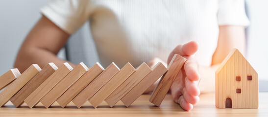 woman hand stop falling wood blocks and protect house model. crisis, fall business, risk, economic r