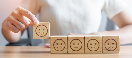 Hand choosing smile face from Emotion block for customer review, good experience, positive feedback, satisfaction, survey, evaluation, assessment, mood, world mental health day concept