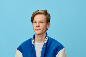 portrait of a handsome pleasantly smiling young man student in a trendy jacket on a blue background