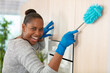 joyful housemaid holding a brush to dust