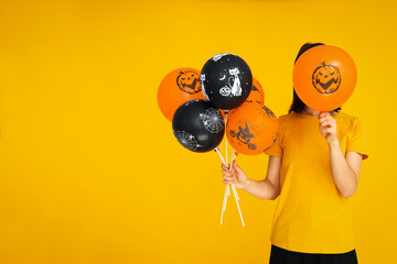 Wall Mural - Concept of Halloween, Woman holds Halloween balloons on yellow background