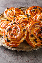 Just Baked Pain Aux Raisins Buns Are Also Called Escargot Or Pain Russe, Is A Spiral Pastry With Custard Cream And Raisin Closeup In The Plate On The Table. Vertical