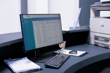 Poster - Electronic archives from administration area of medical clinic displayed on computer screen. Desktop monitor with patient records of hospital. Reception area of empty sanatorium with no people.