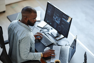 minimal high angle view at african american software developer working with computers and data syste