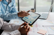 © amnaj - Business team together to make investment planning on digital tablet at the meeting. Close-up of a business consultant pointing to graphs and charts analyzing company growth to expand the product line