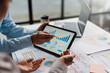 Business team together to make investment planning on digital tablet at the meeting. Close-up of a business consultant pointing to graphs and charts analyzing company growth to expand the product line