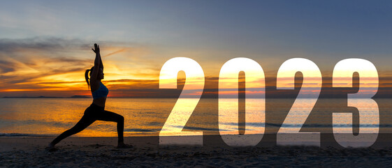 Happy new year card 2023. Silhouette lifestyle woman yoga practicing yoga standing as part of Number 2023 near the beach at sunset. Healthy and Holiday Concept