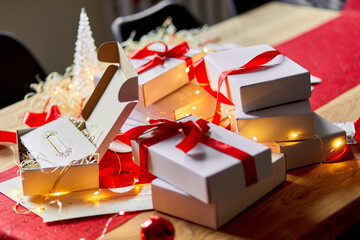 DIY Christmas present wrapping Christmas gift white box with a red ribbon, festive decoration on the table.