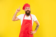 © be free - Happy man in toque and apron got idea keeping finger raised yellow background, chef