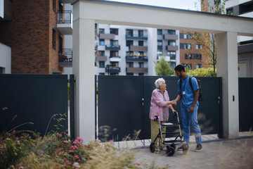 Poster - Caregiver walking with senior woman client in front of nurishing home.