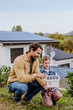 © Halfpoint - Little girl with her dad holding paper model of house with solar panels, explaining how it works.Alternative energy, saving resources and sustainable lifestyle concept.