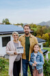 © Halfpoint - Happy family holding paper model of house with solar panels.Alternative energy, saving resources and sustainable lifestyle concept.