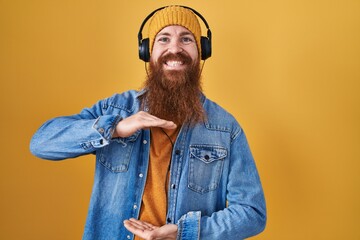 Poster - Caucasian man with long beard listening to music using headphones gesturing with hands showing big and large size sign, measure symbol. smiling looking at the camera. measuring concept.